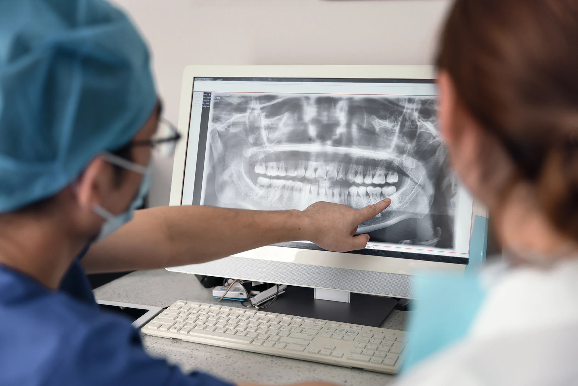 Two dental professionals examining a panoramic dental X-ray on a computer monitor
