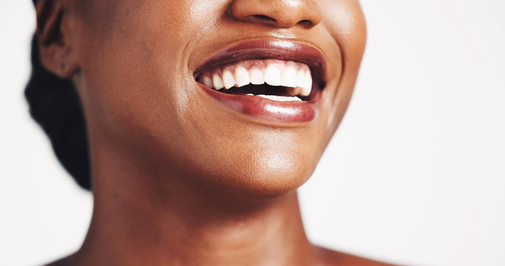 Close-up of a Black woman laughing with a bright smile on a white background