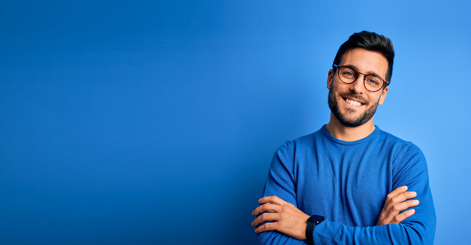 A man glasses arms crossed, against a blue background