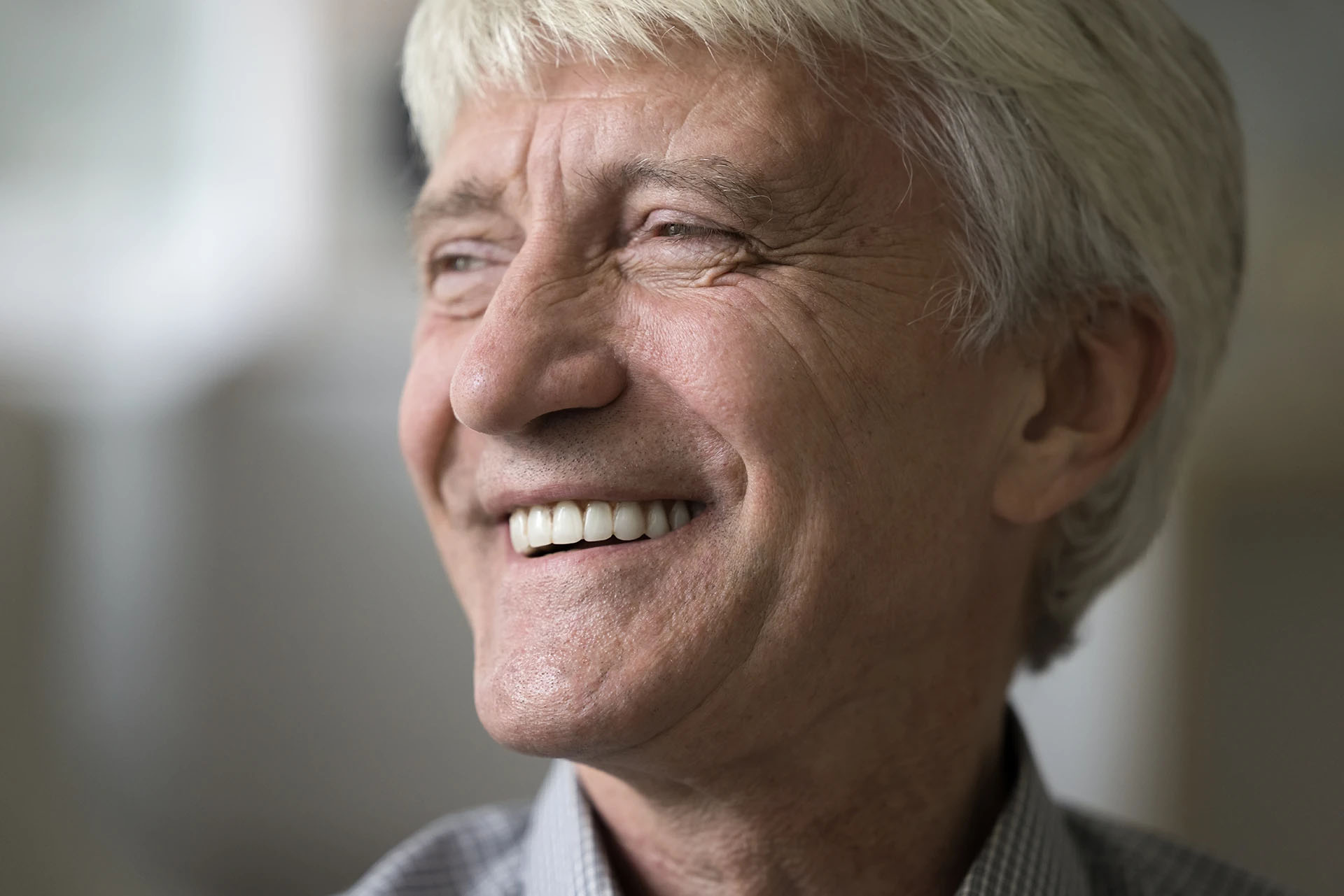 Close-up of a smiling senior man with white hair showing healthy teeth