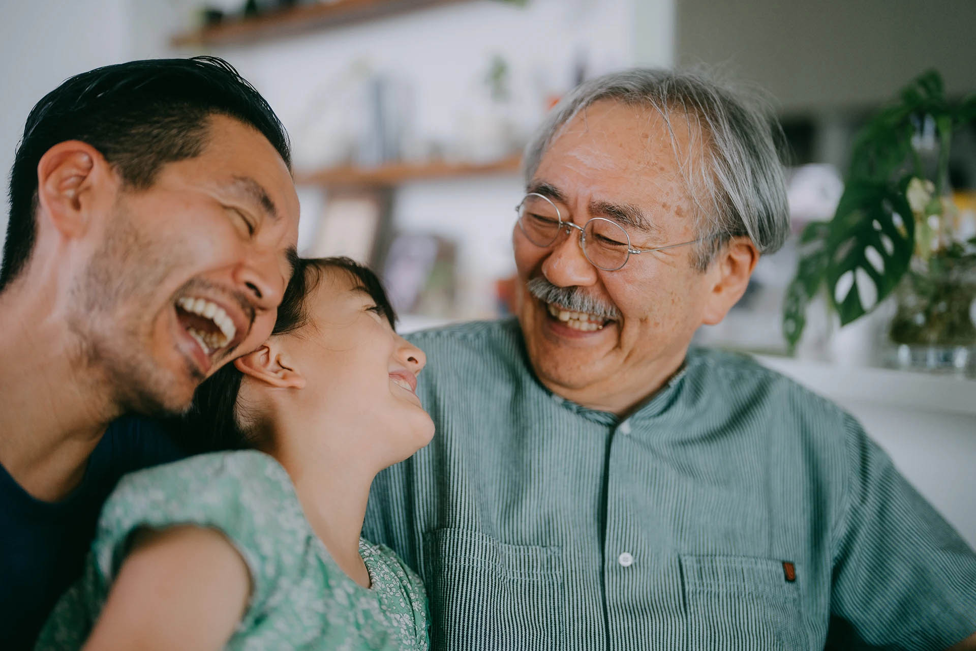 A young father, his daughter and grandfather laughing together at home