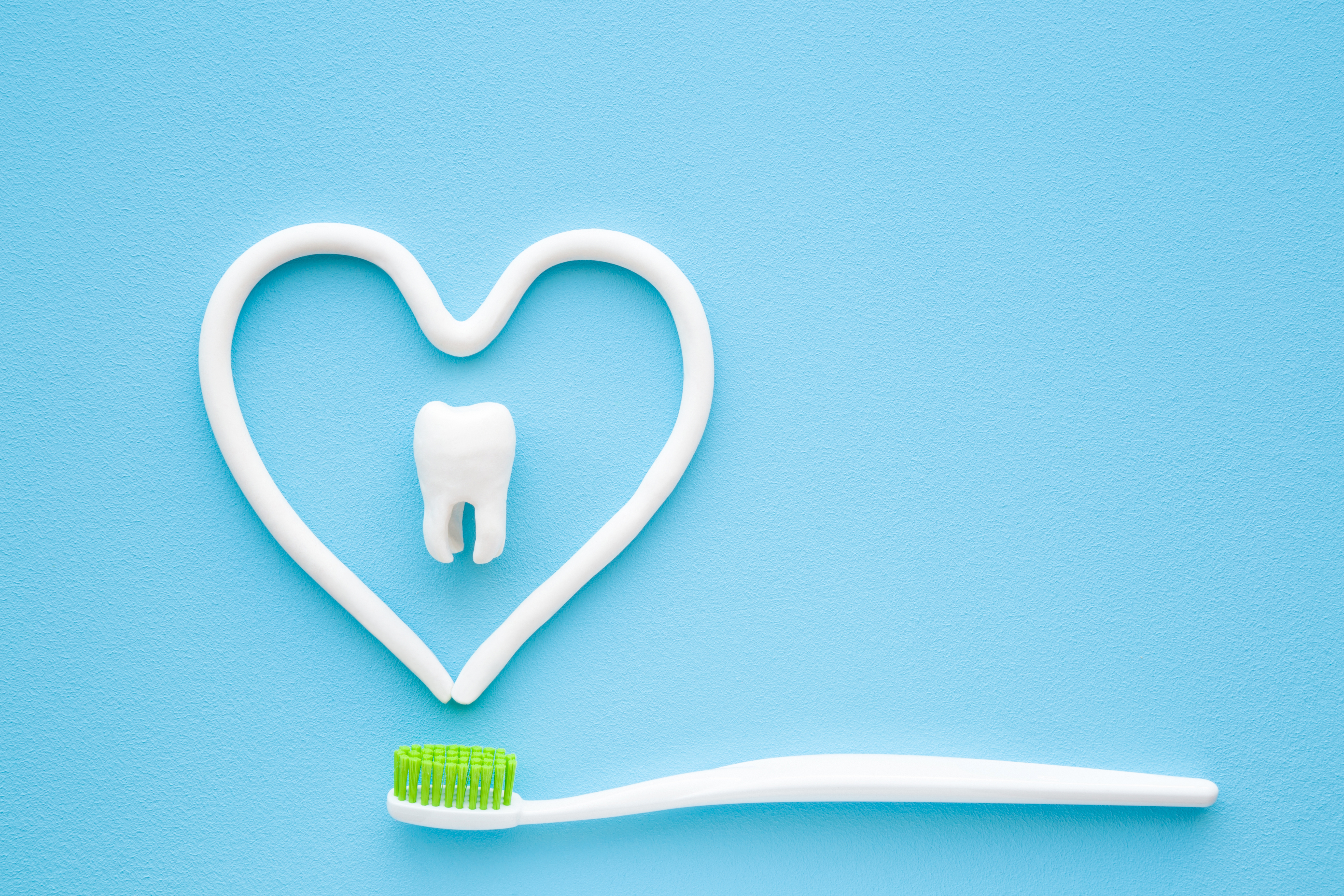 Tooth toothbrush heart shape, against a blue background