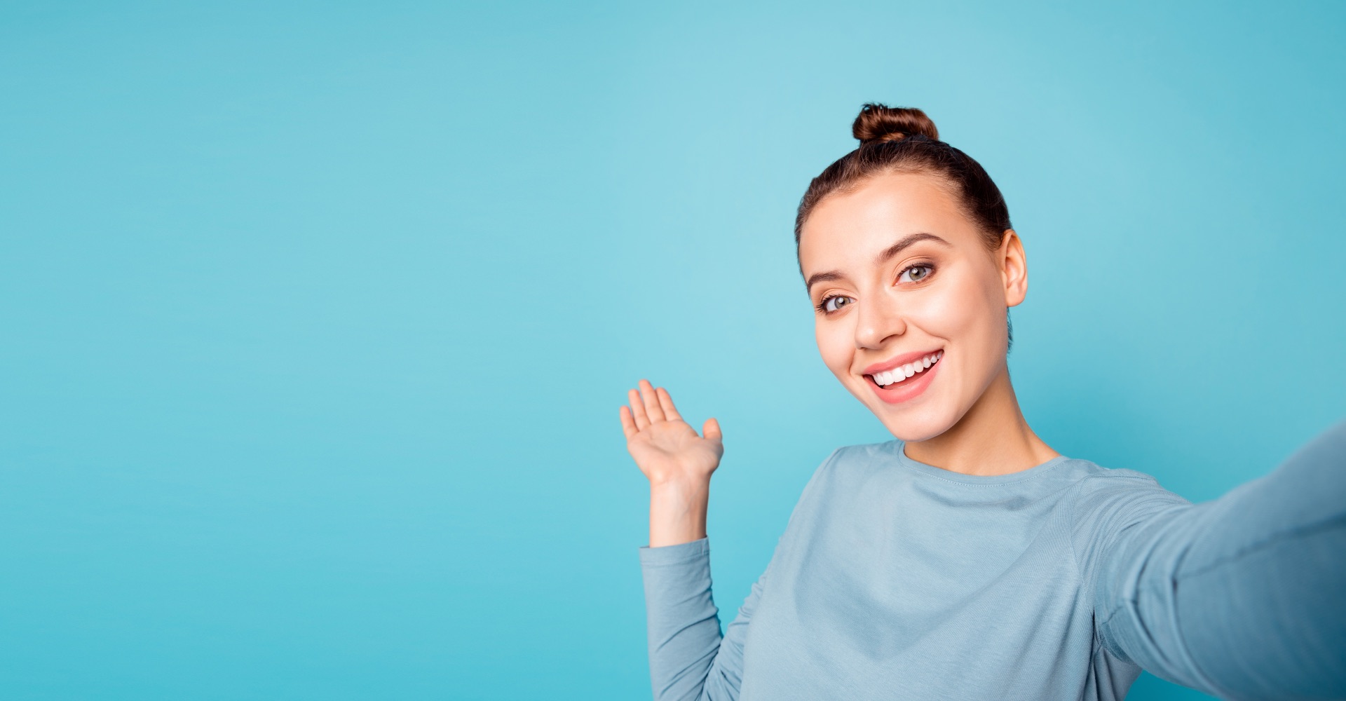 A woman waving, against a teal background