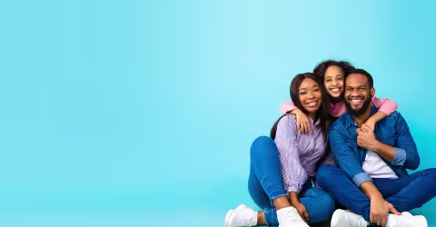 A family four embracing, against a blue background
