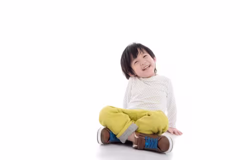 A toddler seated, against a white background