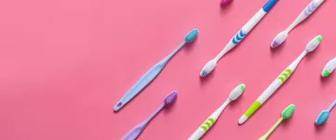 Toothbrushes scattered, against a pink background