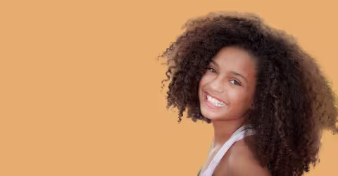 A woman curly hair, against a orange background