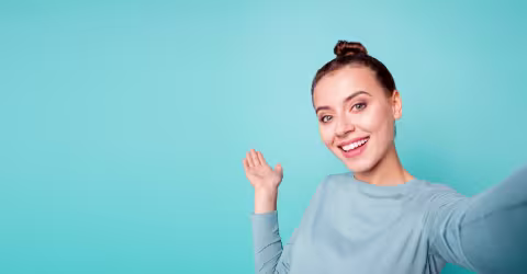 A woman waving, against a teal background